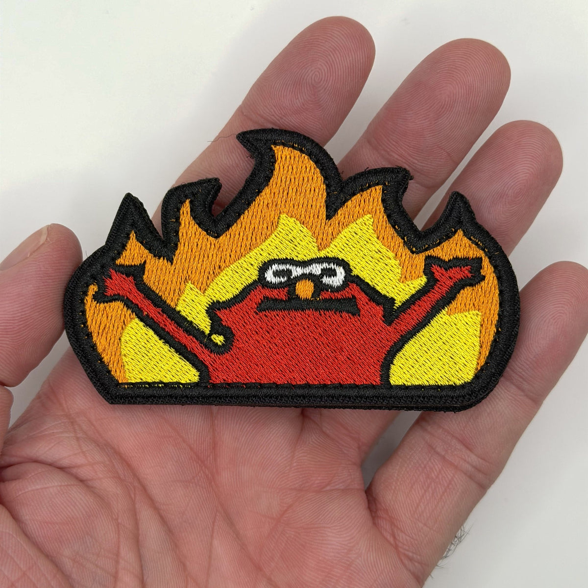 Red Puppet in the Flames embroidered patch held in hand for size, by FOTB Patches